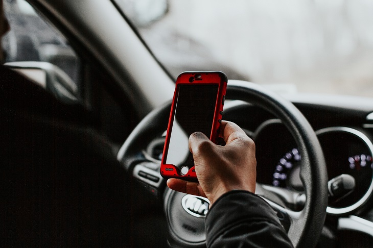 person using phone while behind wheel of vehicle