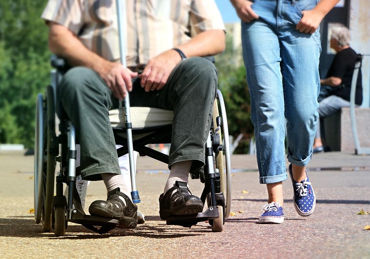 person in wheelchair with cane